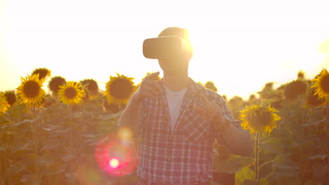 A-man-works-with-virtual-reality-glasses-on-the-field-with-sunflowers.-These-are-new-technologies.